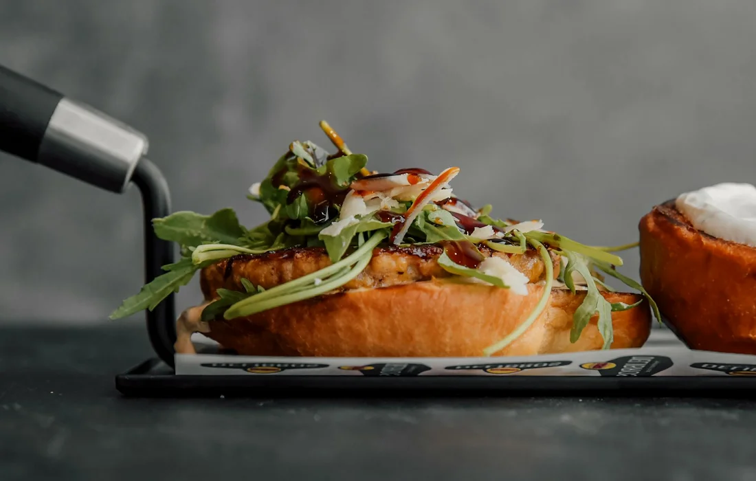 A pastry topped with fresh arugula greens on a dark slate surface, illustrating arugula as a leafy green ingredient.