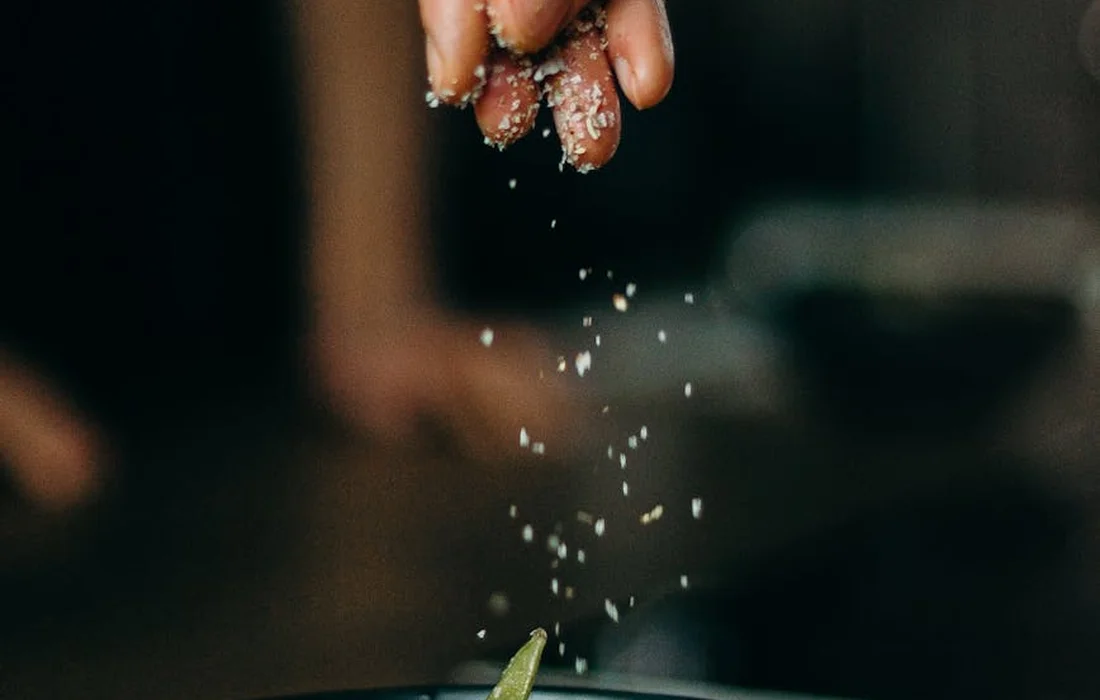 Close-up of a hand sprinkling small white beans into a bowl, symbolizing sustainable, bean-based poultry feeding.