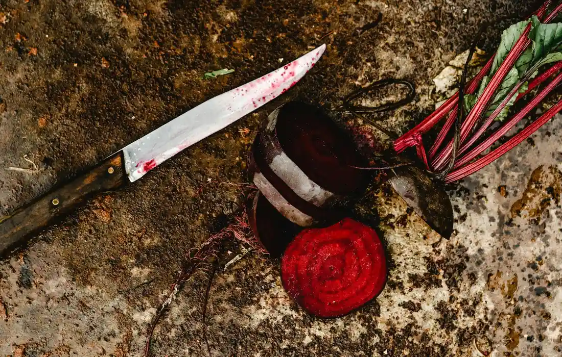 Close-up of a beetroot and its greens on a rough surface with a knife nearby, ready to be prepared as chicken feed.