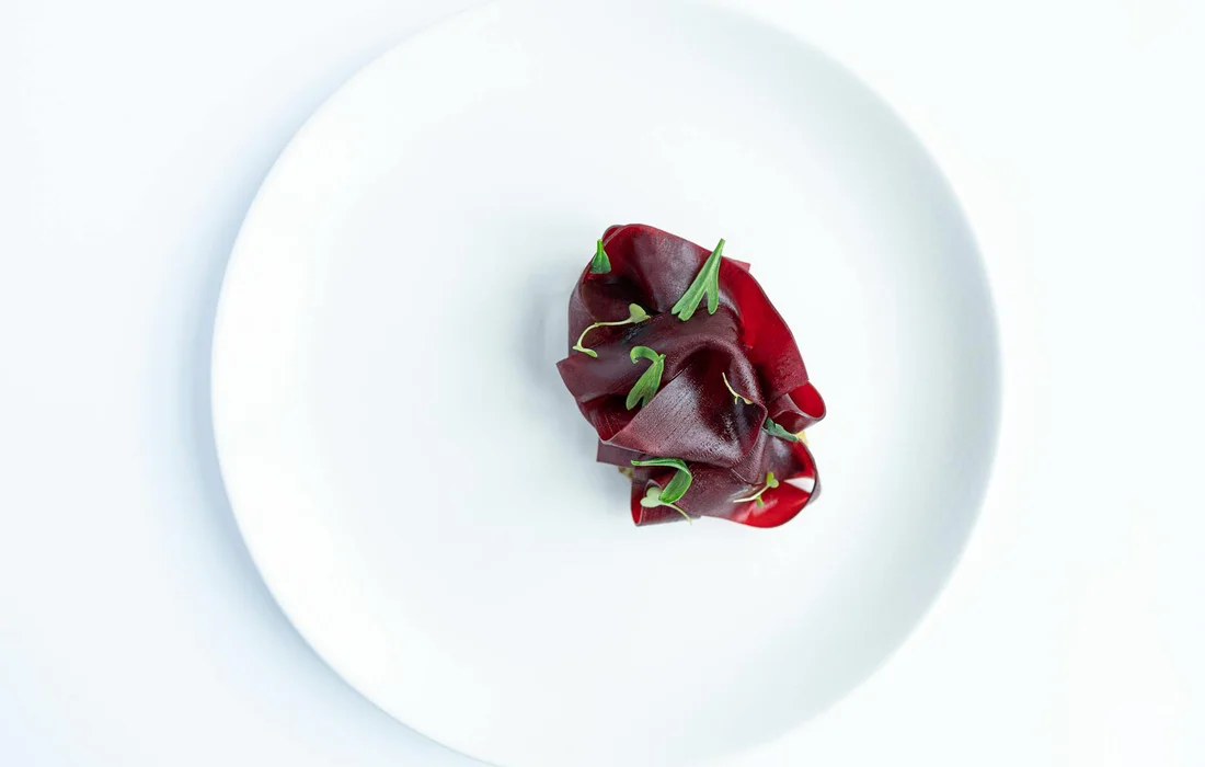 A small portion of red beet slices with green stems on a white plate