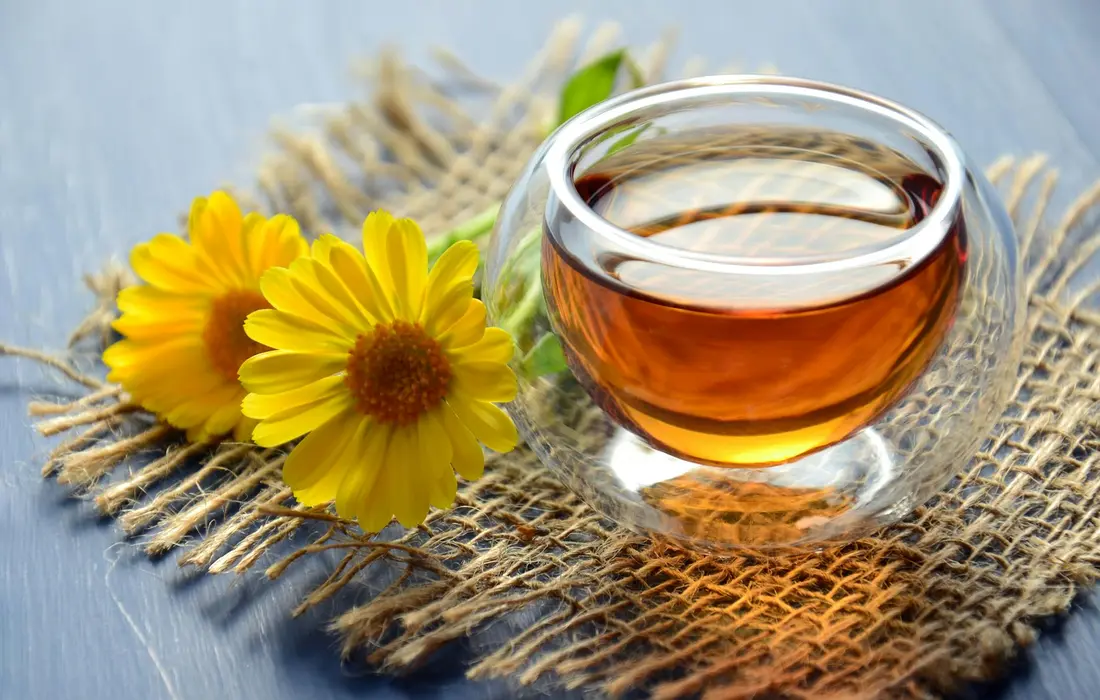 Chamomile flowers and a glass of tea on a woven burlap surface