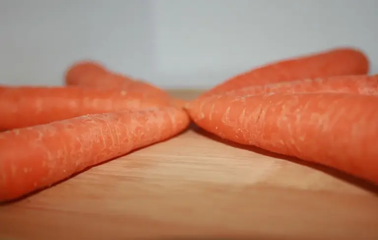 Close-up of fresh orange carrots arranged on a wooden surface.
