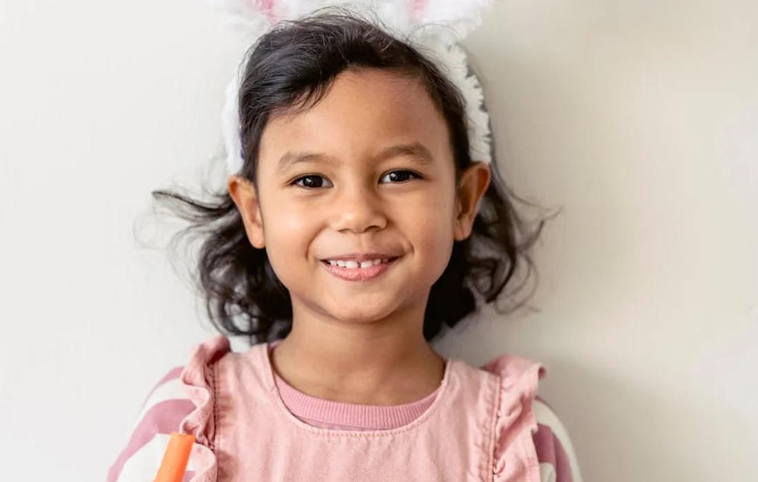 Smiling young girl wearing pink top and fluffy bunny ears
