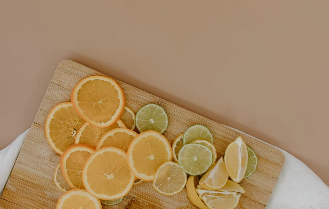 Assorted citrus fruits sliced into rounds and wedges, arranged on a wooden cutting board.