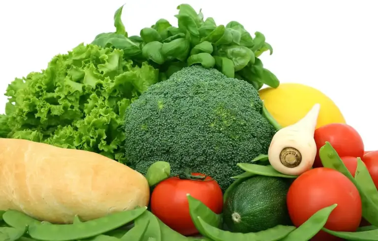 Colorful assortment of fresh vegetables—lettuce, broccoli, tomatoes, cucumber, garlic, and leafy greens.