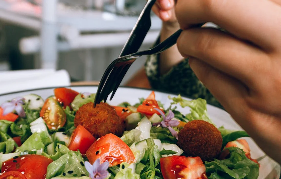 Close-up of a fresh salad on a plate with romaine and mixed greens, a fork poised to pick up a bite.