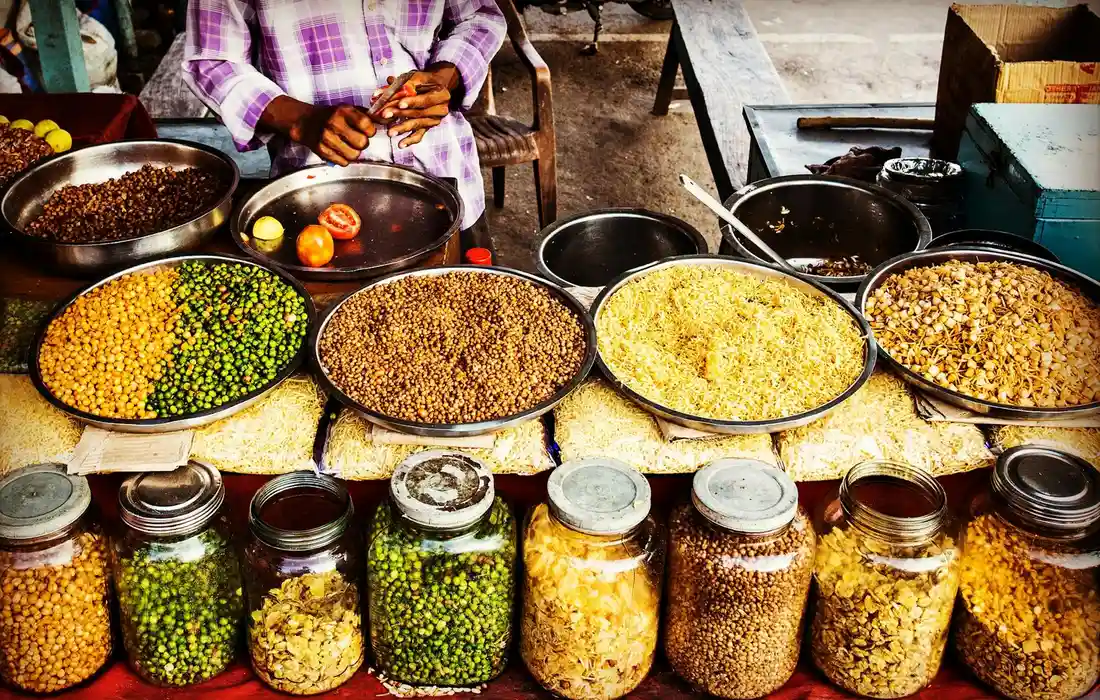 Market stall displaying bowls of mixed legumes and jars of dried legumes.