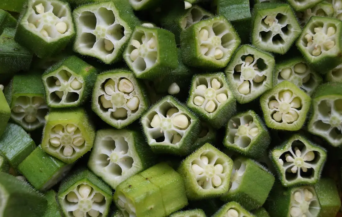 Close-up of cross-sectioned okra pods, showing star-shaped seed cavities inside bright green pods.