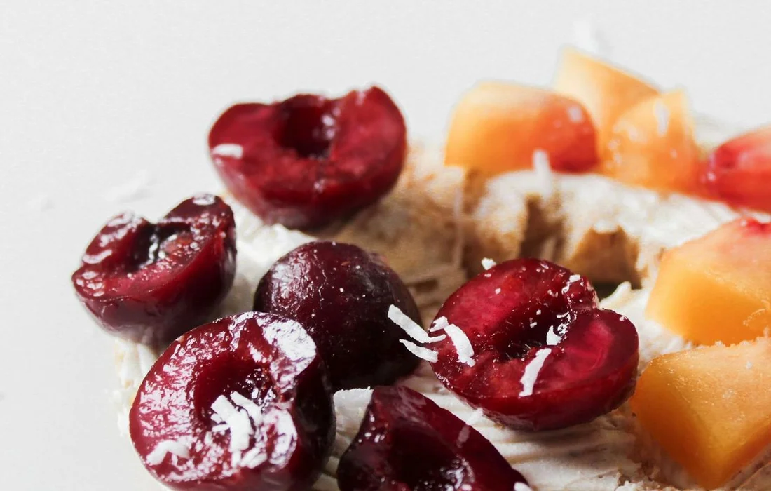 Close-up of sliced peaches and halved cherries on a light background, illustrating fruit as a potential treat for farm animals.