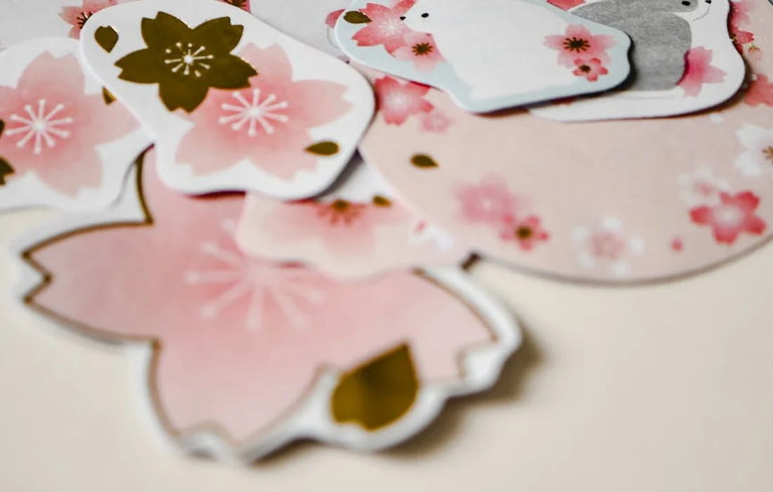 Assorted pink cherry blossom-shaped paper cutouts on a light background