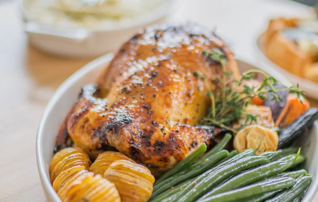 Plate with roasted chicken, green beans, and roasted potatoes topped with herbs