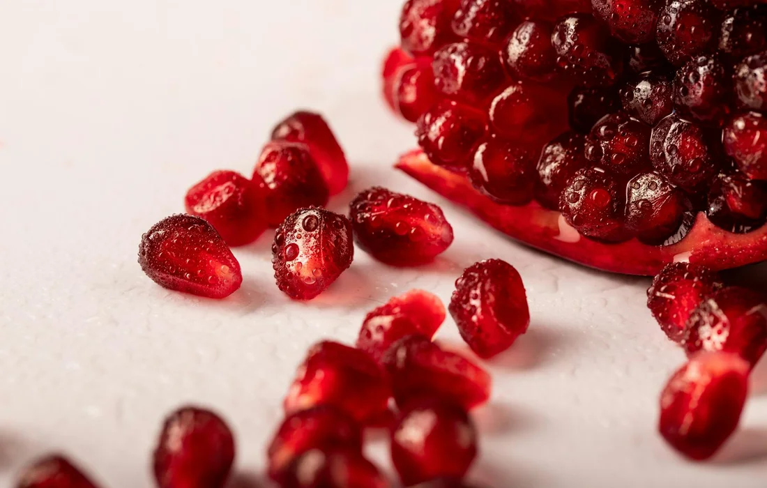 Close-up of scattered red seeds (pomegranate arils) on a pale surface.