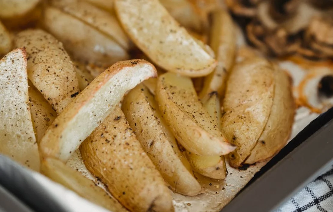 Roasted potato peels and skins in a baking dish, lightly seasoned.
