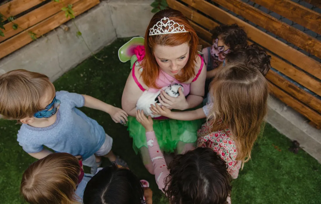Group of children dressed in costumes outdoors around a girl wearing a tiara