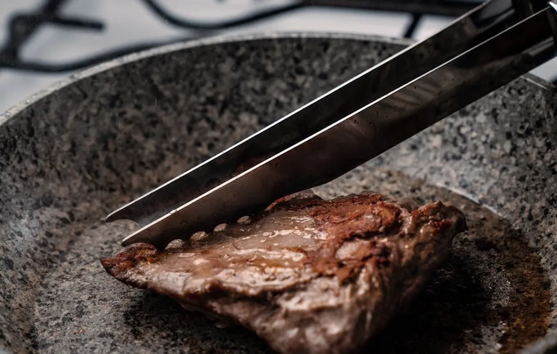 Raw piece of meat on a dark plate with a knife resting on top