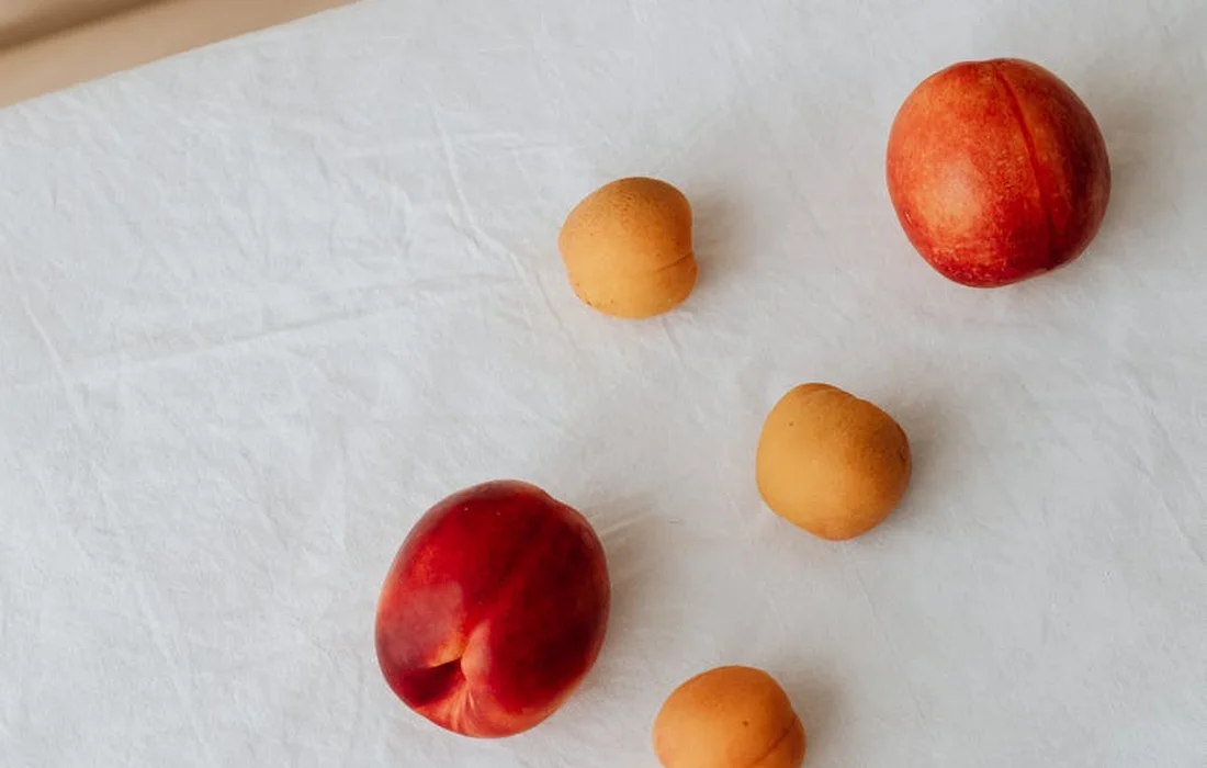 Assorted stone fruits (peaches and apricots) on a white surface