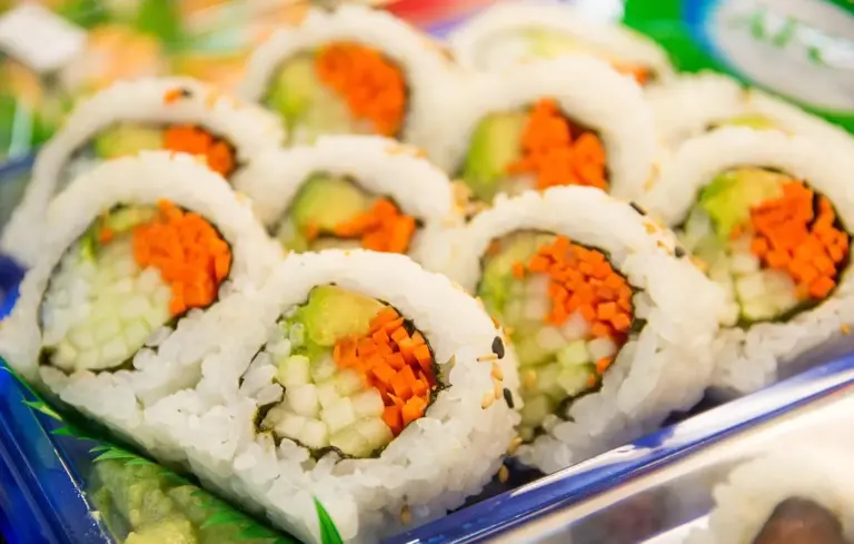 Close-up of sushi rolls with white rice, cucumber, and orange roe.