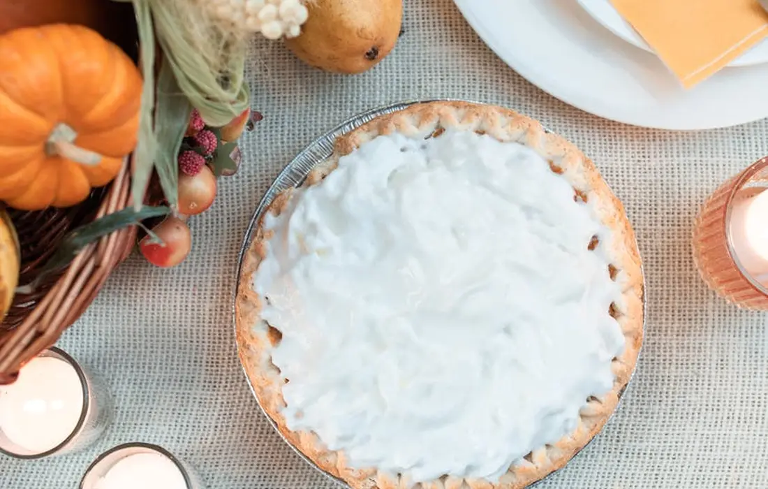 Autumn table with a pie, pumpkins, and candles, providing a harvest-themed backdrop for discussing corn kernel feeding to goats.
